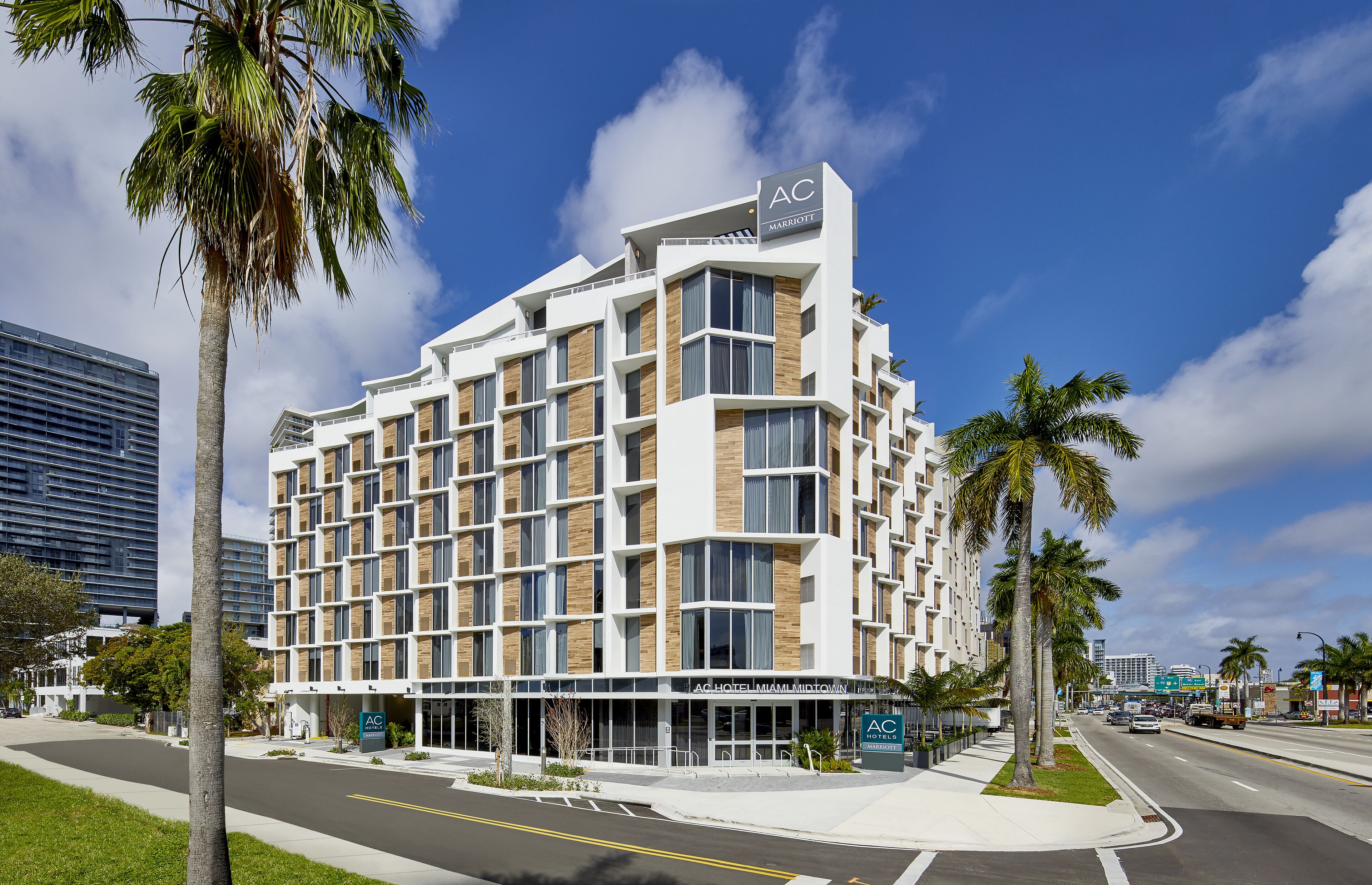 Un hôtel à plusieurs étages au design moderne, reconnaissable à son grand panneau « AC » placé en haut de la façade.