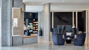 A modern lobby with a seating area, a reception desk, and a display of amenities.