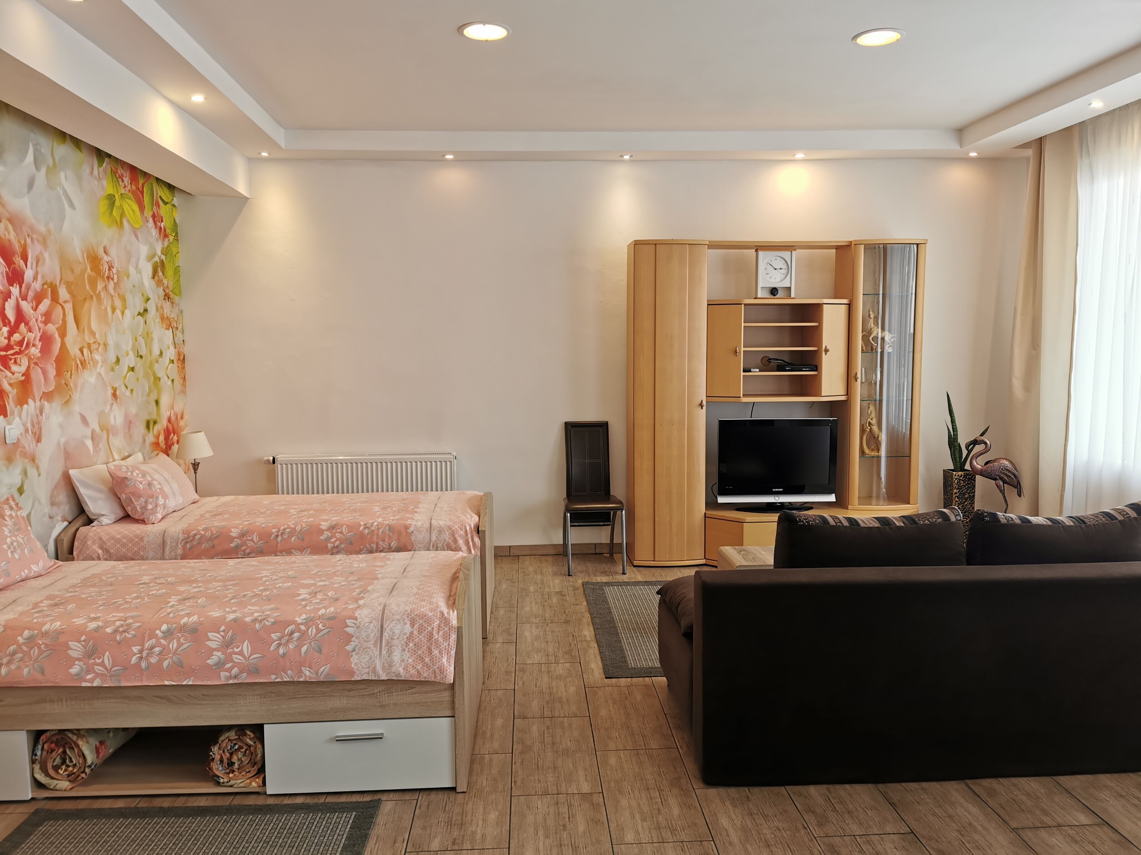 Ein modernes Hotelzimmer mit Bett, Fernseher, Sofa und Kleiderschrank.