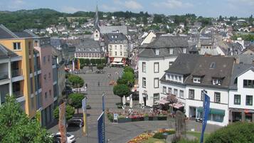 Ein Stadtplatz mit historischen Gebäuden, einem Kirchturm und einem zentralen, offenen Bereich mit Sitzgelegenheiten und Blumenbeeten.
