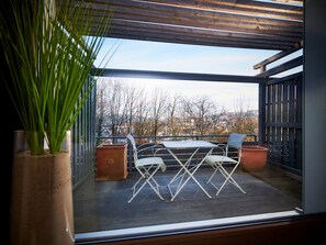 A balcony with a table and chairs, a potted plant, and a view of a cityscape. - criston apartments - central living P (Tuebingen)