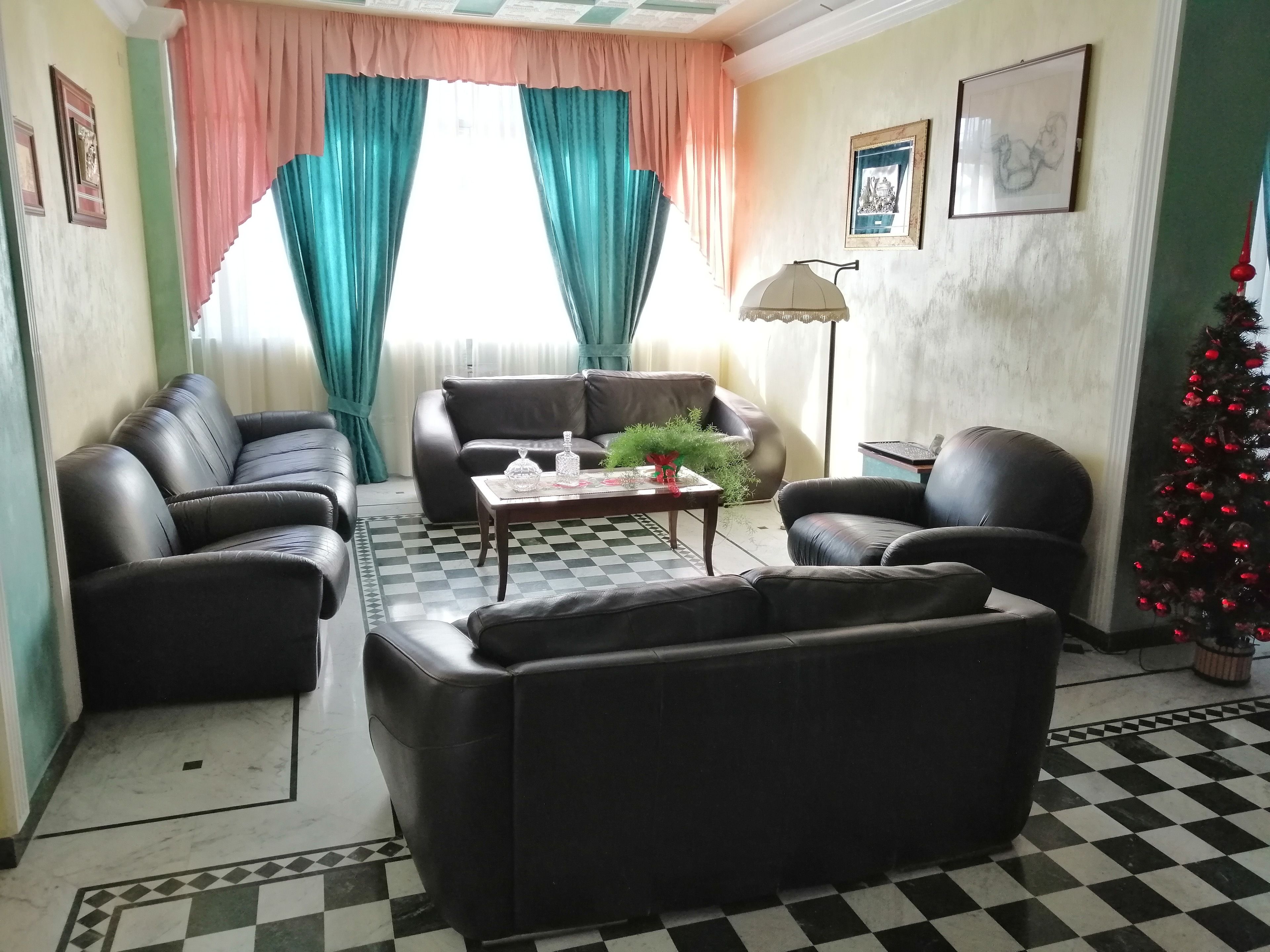 Un salon avec un sol à carreaux, deux canapés en cuir, une table basse agrémentée d’objets décoratifs, une lampe et un sapin de Noël.