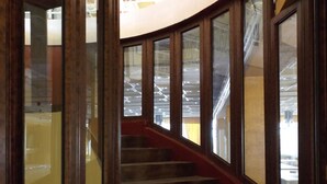 Una escalera con escalones de madera y barandillas de vidrio, que sube a un piso superior.