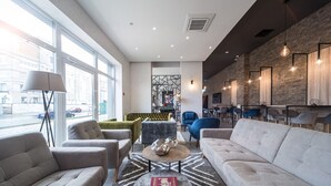 A modern living room with a sofa, armchairs, a coffee table with a book, and a patterned rug. - Amarant Apart Hotel (Kyiv)
