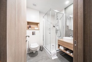 A modern bathroom with a glass-enclosed shower, a wooden vanity, and a white toilet. - Amarant Apart Hotel (Kyiv)