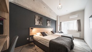 A hotel room with a large bed, two bedside tables, a desk, and a chair. There are two windows with curtains, a radiator, and a hanging light fixture. - Amarant Urban Hotel (Kyiv)