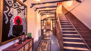 A staircase with wooden steps and a handrail, leading to a room with a wooden ceiling and a chandelier. - Netuk House (Gangtok)