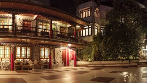A traditional building with a curved facade, multiple windows, and a balcony area with seating. - Netuk House (Gangtok)