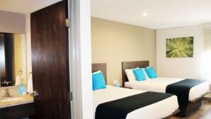 A hotel room with two beds, a wooden floor, a beige wall, and a painting.