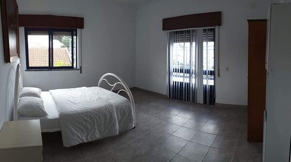 Um quarto com cama, janela e porta.