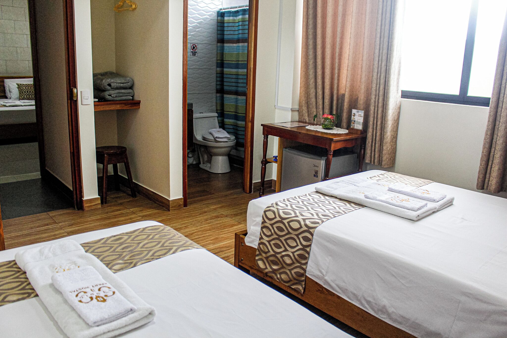 A hotel room with two beds, a bathroom, and a small table with a towel.