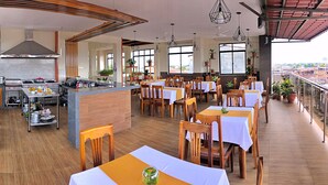 A restaurant with a kitchen area, dining tables, chairs, and potted plants. - Studio 69 (Iquitos)