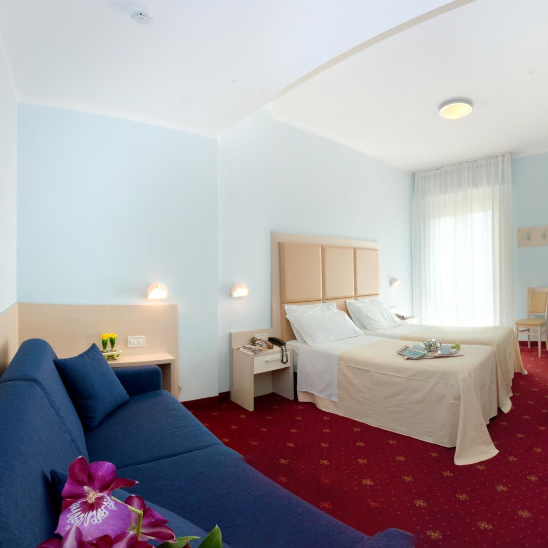 Een hotelkamer met een bed, een bank, een bureau en een stoel.