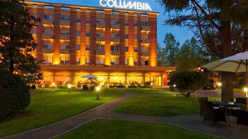 A multi-story hotel with a prominent 'COLUMBIA' sign, a well-maintained lawn, and outdoor seating area.