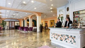 Een hotellobby met een receptiebalie, een zithoek en een bar.