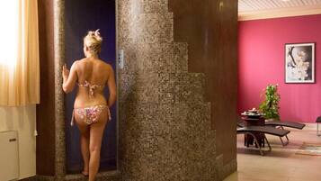 A person exiting a room with a tiled wall and a pink wall with a framed picture.
