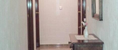 Un pasillo con un banco de madera, un espejo y una puerta al final.