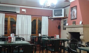 Un comedor con mesas y sillas, un televisor montado en la pared y una chimenea.