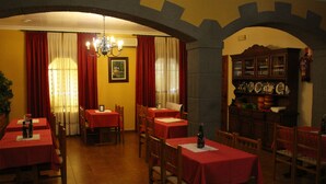 Un comedor con mesas dispuestas para el servicio, una araña y un aparador con cristalería.