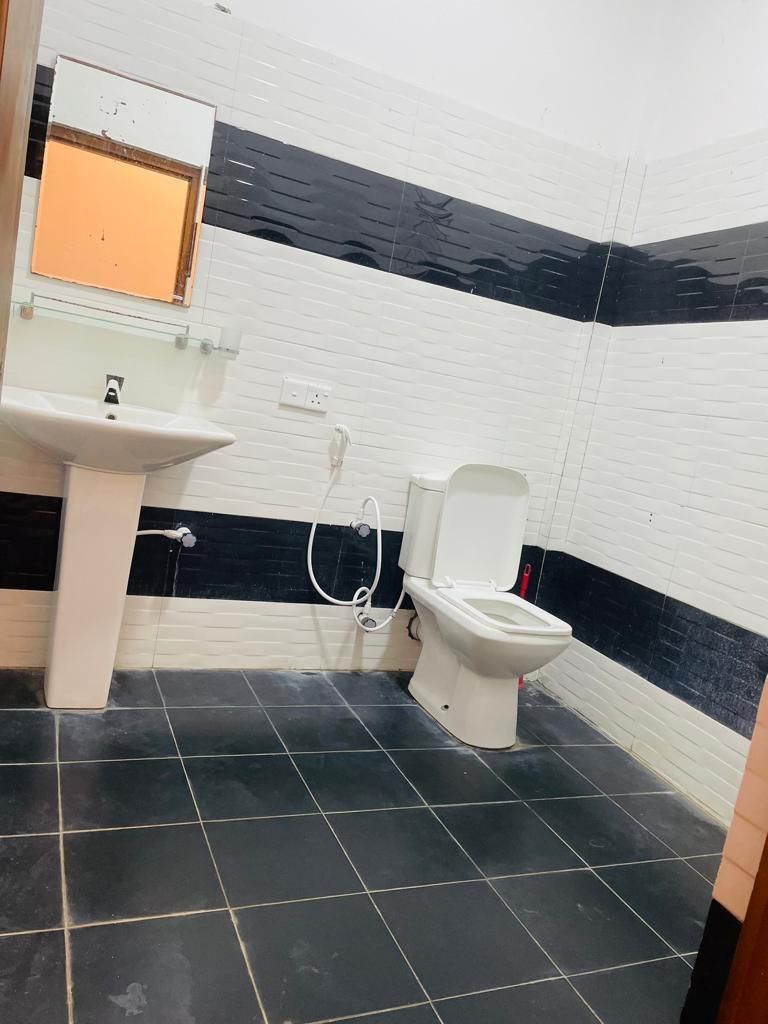 Une salle de bain avec un lavabo blanc, des toilettes et un miroir.