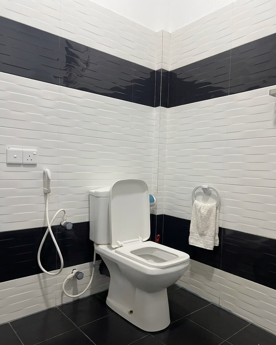 A modern bathroom with a white toilet, a glass shower enclosure, and a towel rack.
