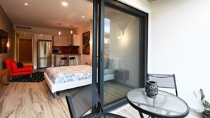 A modern bedroom with a bed, a red chair, and a dining area with a table and chairs. - Soul fase 2 (Playa del Carmen)