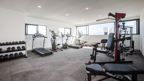 A gym with treadmills, elliptical machines, dumbbells, and weightlifting equipment. - Icono 405 (Playa del Carmen)