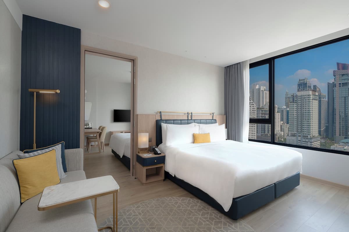 Une chambre d’hôtel moderne dotée d’un grand lit, d’un coin salon et offrant une vue sur la ville.