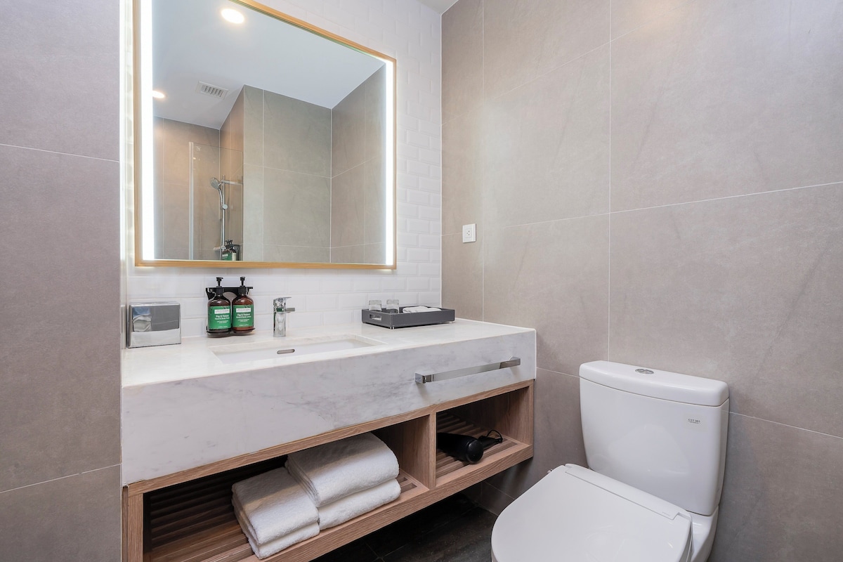 Une salle de bain moderne avec un lavabo en marbre, un grand miroir et des toilettes.
