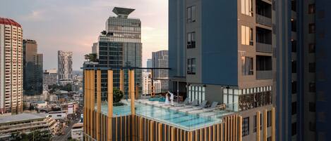 A high-rise building with a rooftop pool, modern architecture, and a cityscape view.