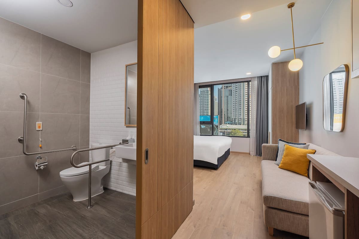 Une chambre d’hôtel moderne équipée d’une douche, de toilettes, d’un lit et offrant une vue sur la ville.