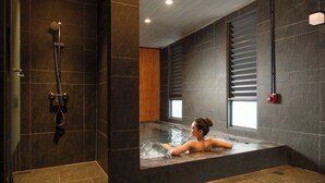 Un baño moderno con una bañera grande, zona de ducha y ventana que proporciona luz natural.