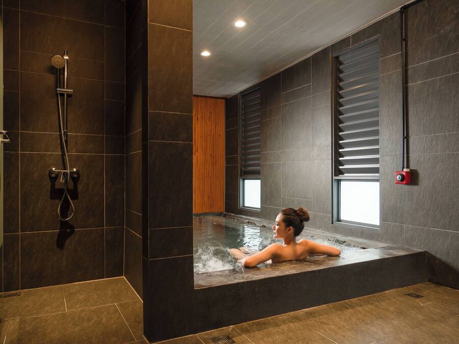 Ein modernes Badezimmer mit einer großen Badewanne, einer Duschkabine und einem Fenster für natürliches Licht.