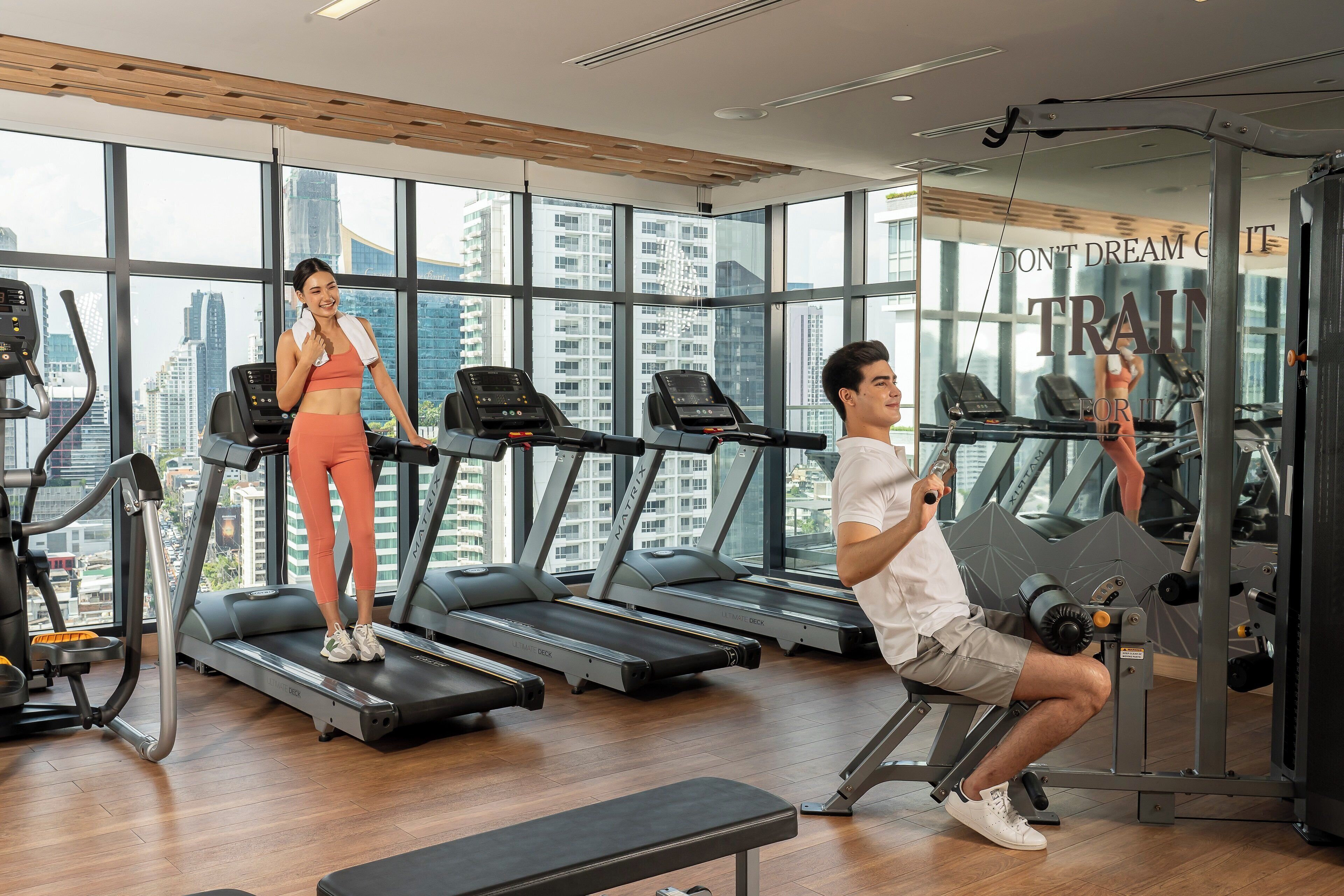 Un gimnasio con cintas de correr, una máquina de pesas y un banco.