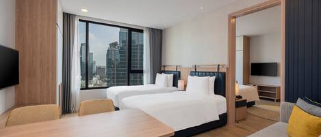 A hotel room with two beds, a dining table, and a sofa.