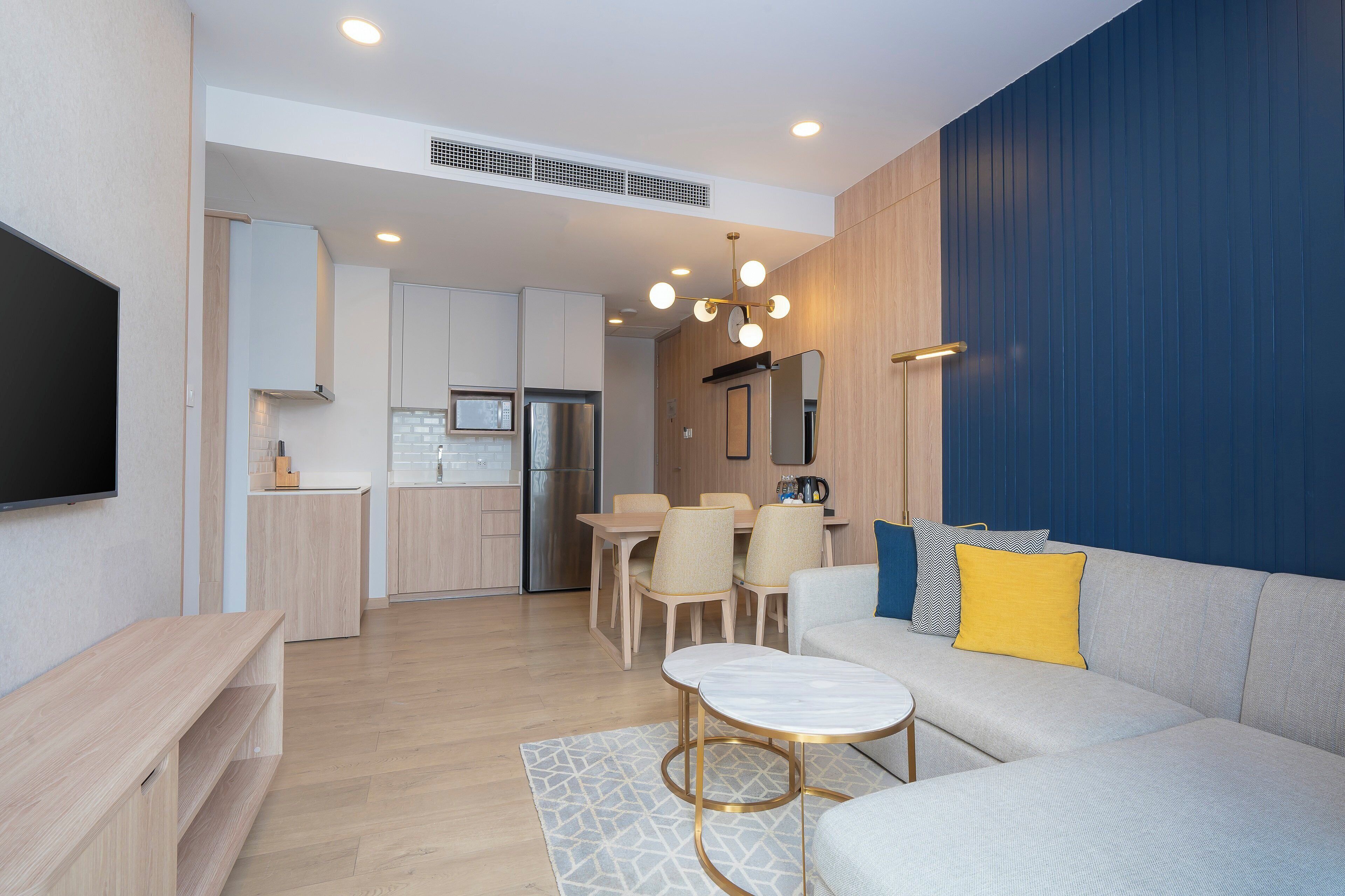 A modern living room with a sofa, a coffee table, and a dining area with chairs and a table.