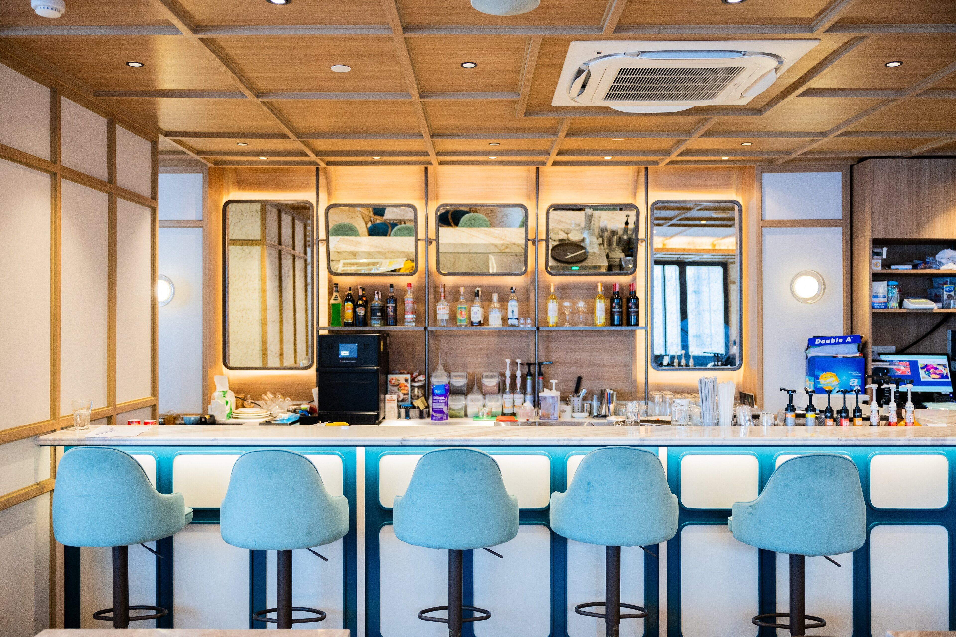 A bar area with a counter, bar stools, and shelves with bottles.