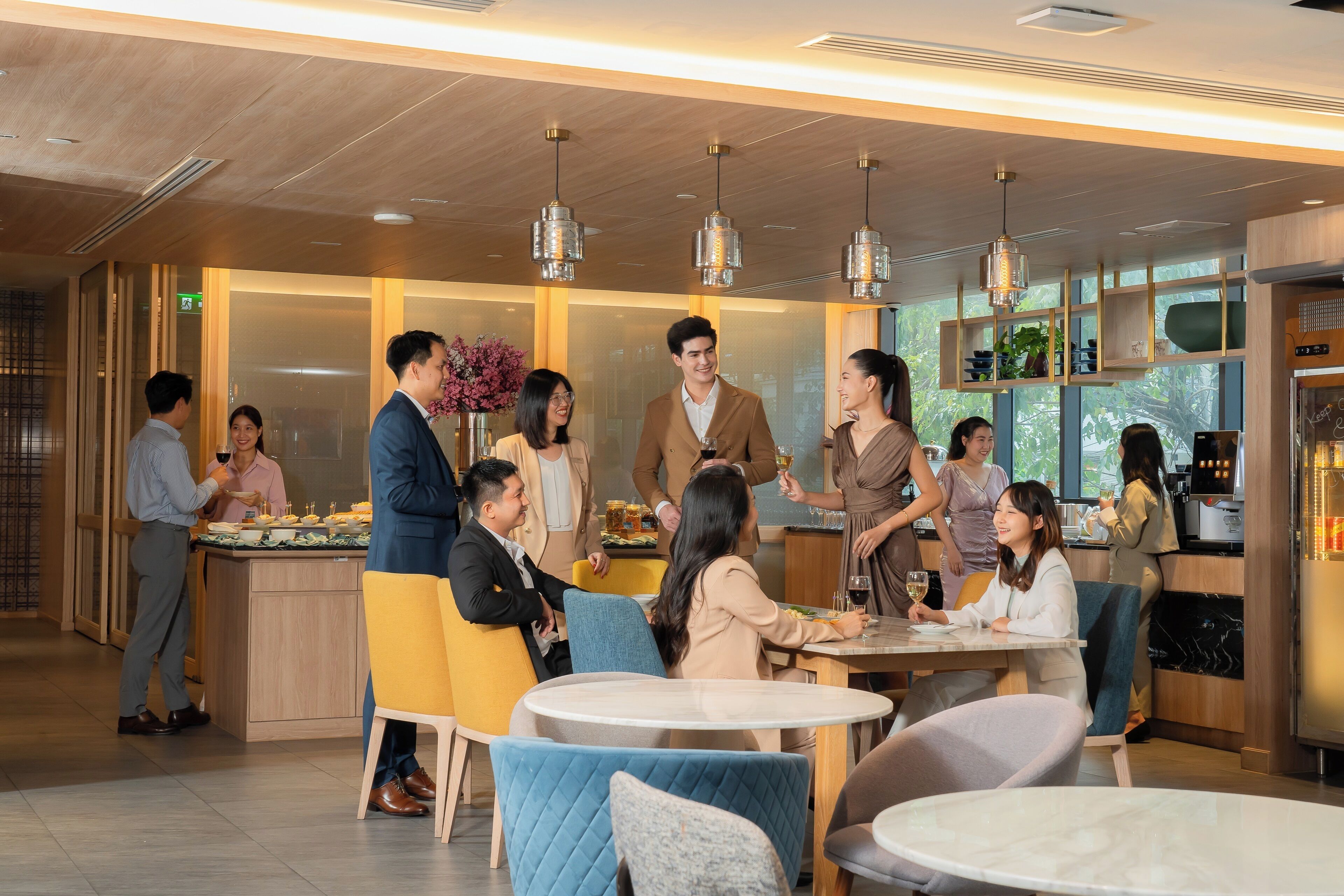 A modern restaurant with round tables and comfortable seating, a bar area, and a visible kitchen.