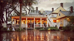 A waterfront property with a covered porch, outdoor seating, and a staircase leading to a second level.