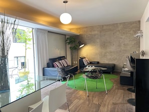A modern living room with a glass table, a sofa, a coffee table, and a lamp.