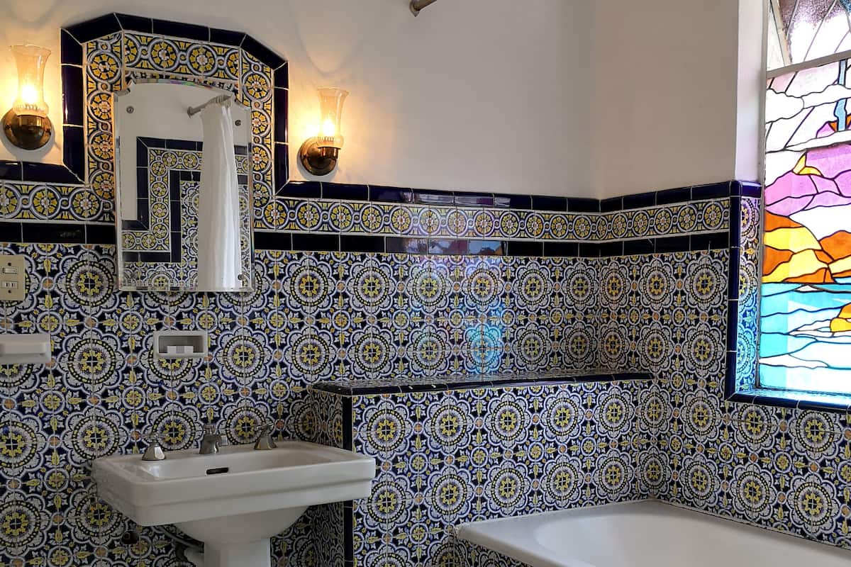 A bathroom with a white sink, a bathtub, and a decorative tiled wall.