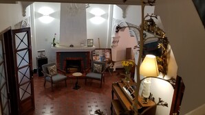 Een gezellige woonkamer met een open haard, twee fauteuils, een bijzettafeltje en een lamp.