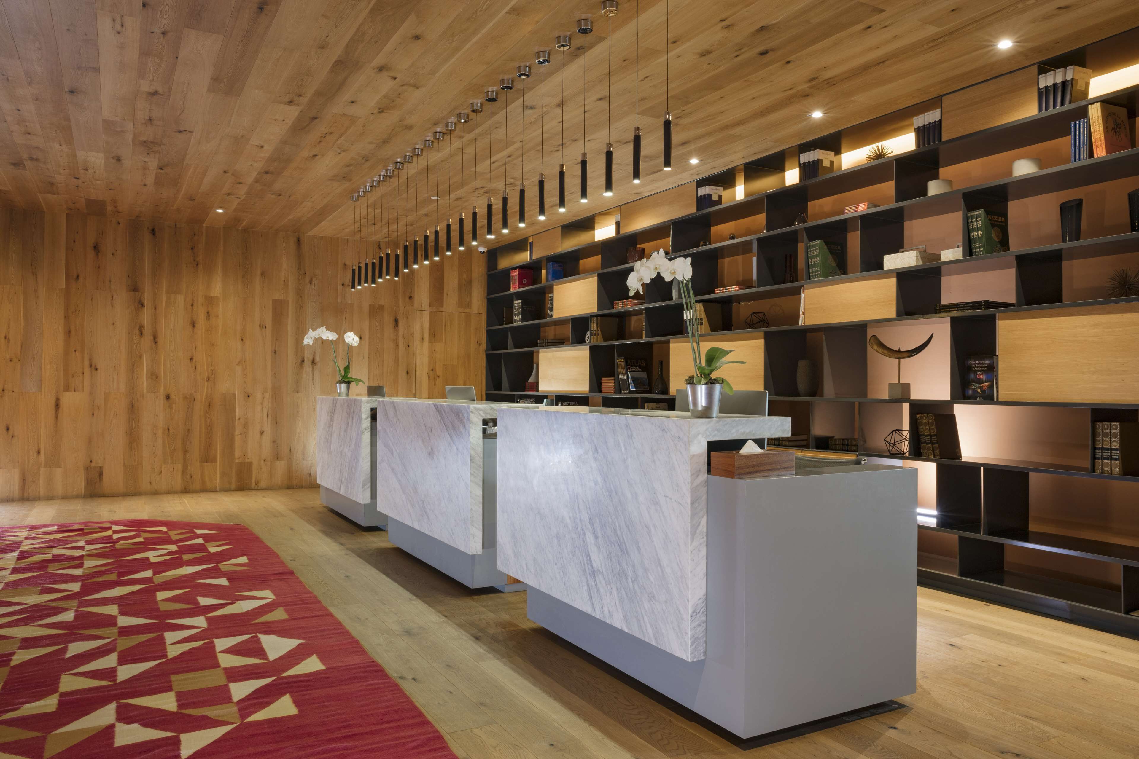 A reception area with a marble counter, wooden ceiling, and shelves with books and decorative items.