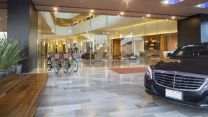 A modern interior with a car and bicycles, glass walls, and a wooden bench. - Hyatt Centric Campestre Leon (León)