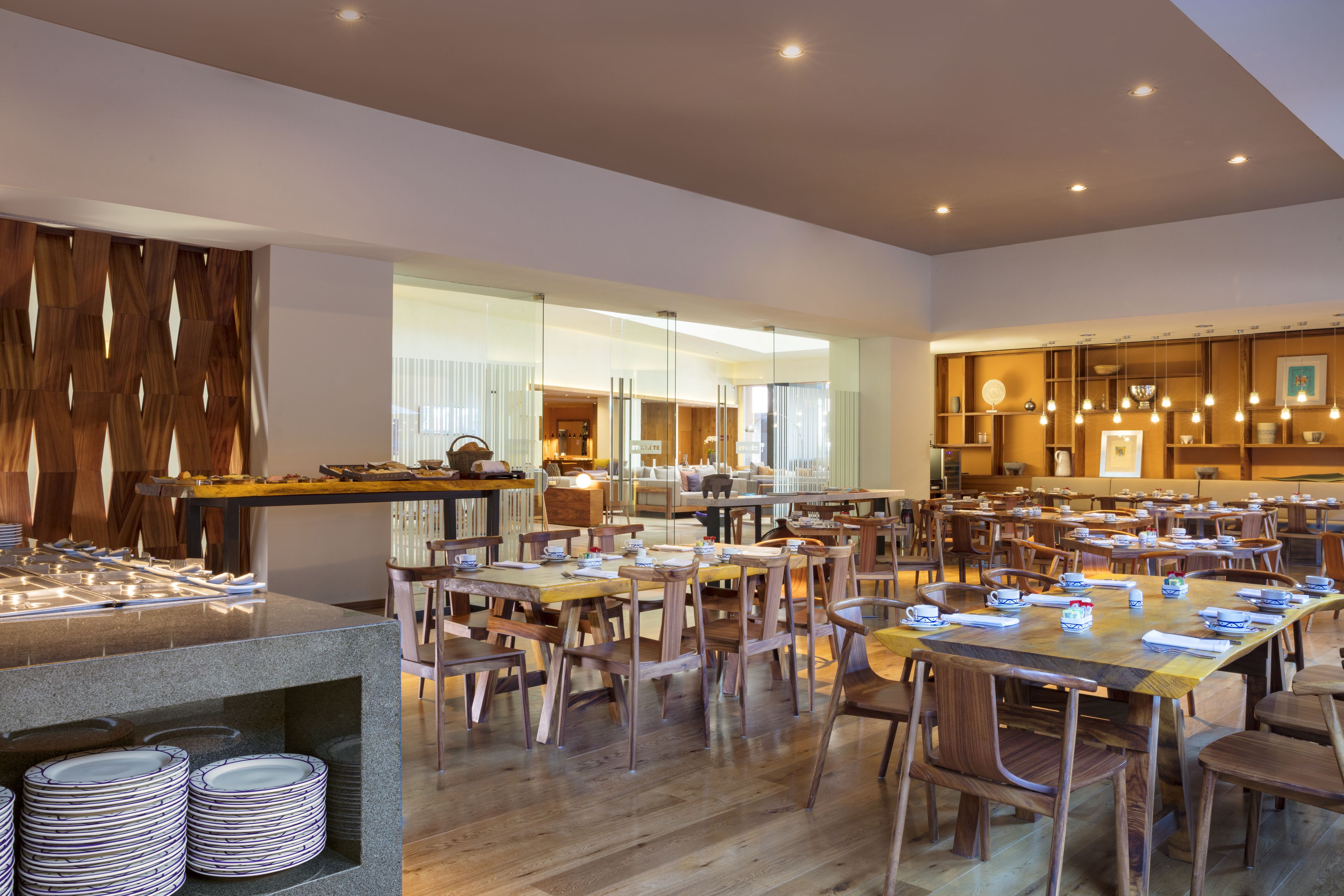 Un grand espace dédié à la salle à manger, avec plusieurs tables et chaises, un buffet et une vue sur la cuisine en arrière-plan.