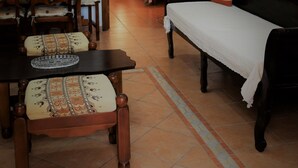 Una sala acogedora con una mesa de madera, sillas, un sofá y una cama al fondo.