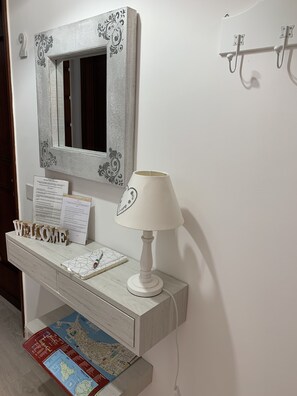 A reception desk with a white lamp, a framed mirror, and a welcome sign.