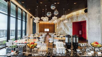 A spacious dining area with round tables, chairs, and a buffet setup.