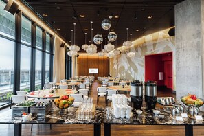 A spacious dining area with round tables, chairs, and a buffet setup.
