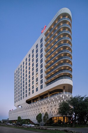Een modern hotel met opvallende, golvende architectuur, meerdere balkons en een prominente entree.